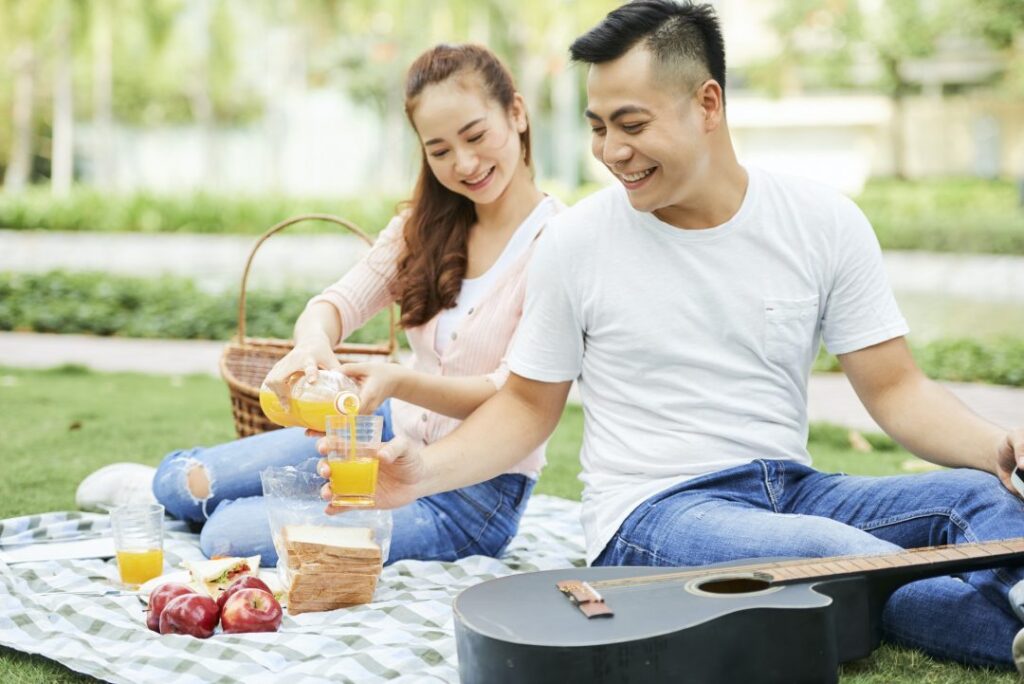A happy couple enjoying premium JUGO cold-pressed juices during a luxury outdoor picnic, featuring a healthy and vibrant lifestyle.